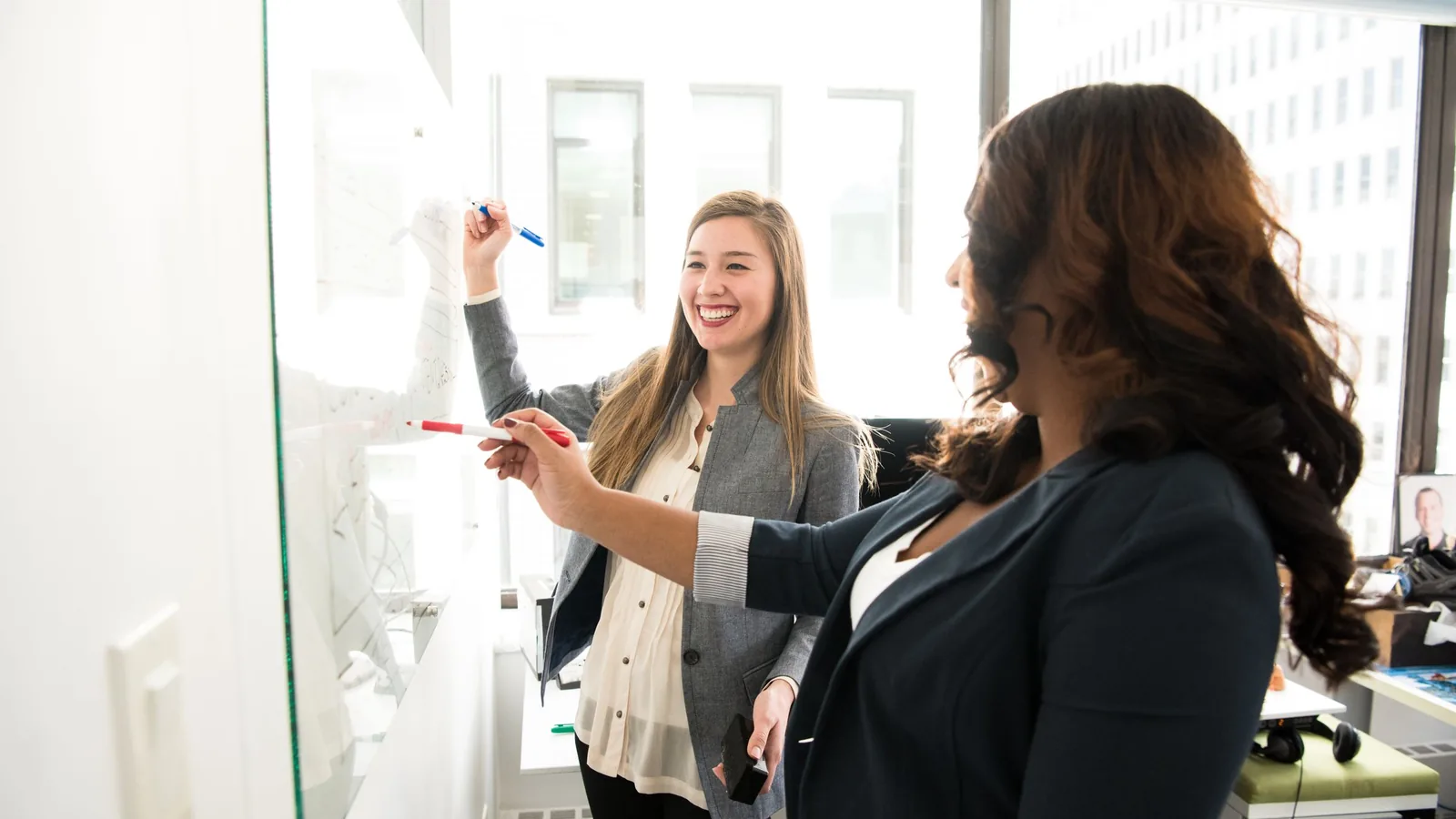 Two colleagues mapping out a process together at a whiteboard.